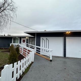 A suburban house with a ramp leading to the front entrance, featuring a white fence and garage.