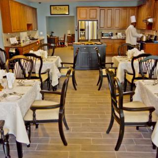 A restaurant dining area with neatly set tables and a chef working in the kitchen.