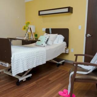 A well-organized hospital room featuring a single bed, a chair, and medical equipment.