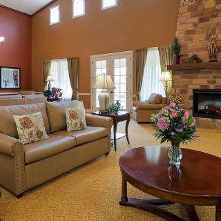A cozy living room featuring a sofa, coffee table with flowers, and a warm fireplace.