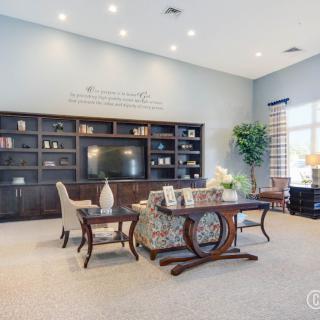 A spacious living room featuring elegant furniture, built-in bookshelves, and a large television.