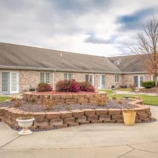 A brick residential building with a landscaped courtyard featuring flowerbeds and potted plants.
