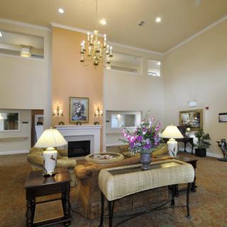 A spacious and elegantly decorated lobby with a chandelier, fireplace, and comfortable seating.