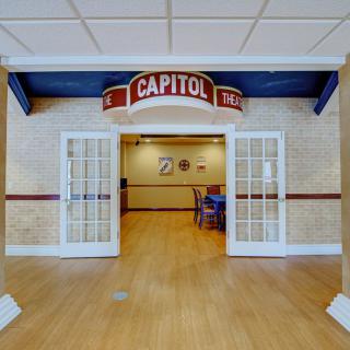 Entrance to a room with a 'Capitol' theater-style sign overhead and glass double doors.