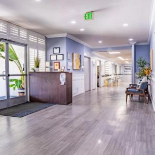 A modern lobby with wood flooring and stylish decor, featuring a reception desk and hallway.