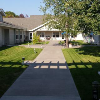 A sunny day view of a residential house with a pathway and well-maintained lawn.