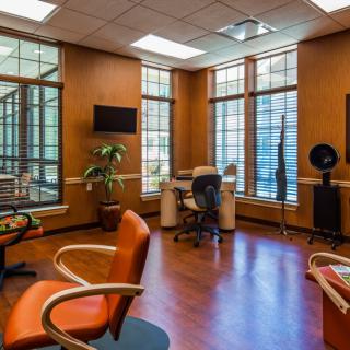 A modern office space with comfortable seating, large windows, and wooden flooring.