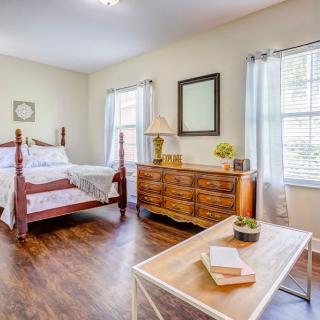 A bright bedroom with wooden flooring, featuring a bed, dresser, and ample natural light.