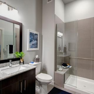 A modern bathroom with a sleek vanity, large mirror, and a glass-enclosed shower.