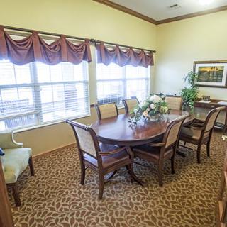 A cozy dining room with a wooden table and chairs, decorated with indoor plants and artwork.