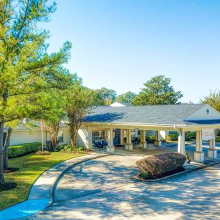 A sunny view of a clubhouse surrounded by greenery and a curved driveway.