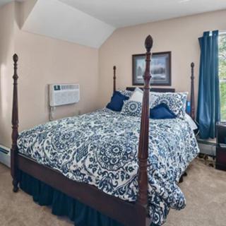 A cozy bedroom with a four-poster bed featuring blue and white bedding and tasteful decor.