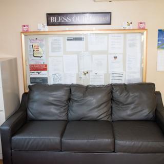 A leather couch in front of a bulletin board in an office waiting area.
