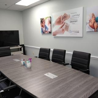 A modern conference room featuring a large wooden table, black seating, and wall art to enhance the professional atmosphere.