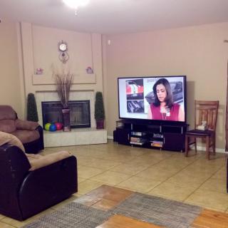 A cozy living room featuring a large flat-screen TV and a fireplace.