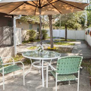 A peaceful backyard patio setup with a glass table, chairs, and an umbrella.