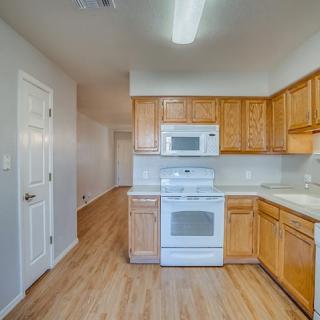 A modern kitchen with wooden cabinets and white appliances, featuring an oven and microwave.