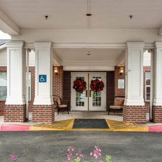 An entrance of a building with columns, adorned with decorative wreaths and a covered walkway.