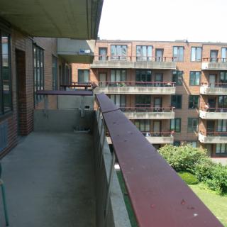 A view from a balcony overlooking an apartment complex with green space.