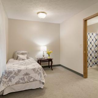 A minimalist bedroom with a single bed, nightstand, and lamp.