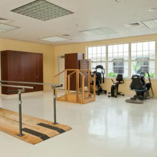 A rehabilitation therapy room equipped with parallel bars and exercise machines.