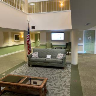 A lobby area with a sofa, American flag, and seating arrangement.