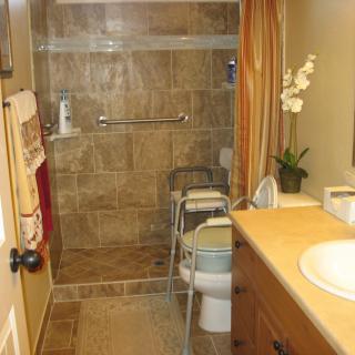 A bathroom with tiled shower, toilet, and sink area.