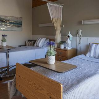 A hospital room with two patient beds, equipped with medical equipment and a dividing curtain.