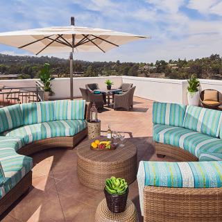 An inviting outdoor patio with circular seating, a large umbrella, and decorative plants.