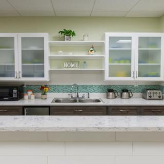 A modern kitchen with sleek cabinetry, open shelves, and a marble countertop.
