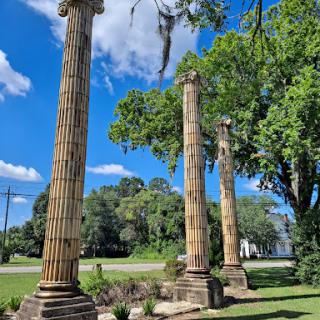 Remnants of grandeur: A trio of ancient columns standing tall against the blue sky, surrounded by lush greenery.