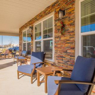 A sunny porch with comfortable seating and a stone exterior.
