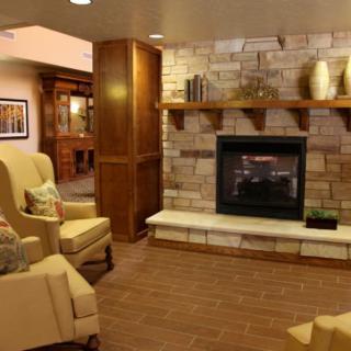 A cozy living room featuring a fireplace, armchairs, and wooden accents.