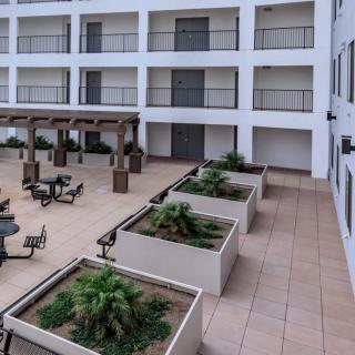 A view of a hotel courtyard with outdoor seating and planters, surrounded by balconies.