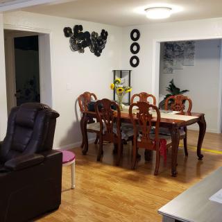 A cozy dining room with a wooden dining table and chairs, complemented by wall decorations and a wooden floor.