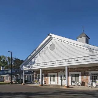 A sunny view of a residential building with a porch and classic architecture.