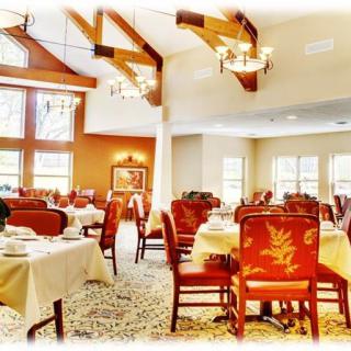 A cozy and elegant dining room with wooden beams, chandeliers, and neatly arranged tables and chairs.