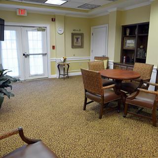 A comfortable waiting area with seating and a table, featuring decorative elements like a plant and bookshelf.
