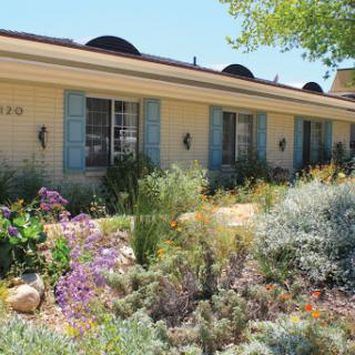 A charming house with a beautifully landscaped garden featuring colorful flowers and lush greenery.