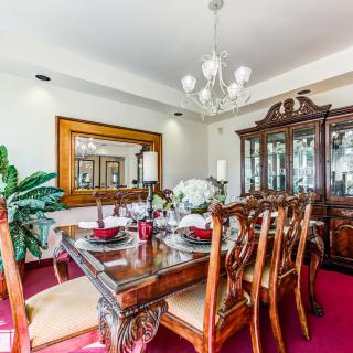 An elegant dining room with a polished wooden table, ornate chairs, and a chandelier.