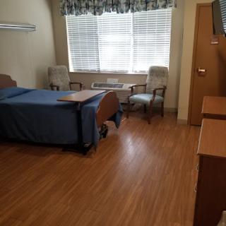 A spacious and well-lit hospital patient room with a bed and seating area.