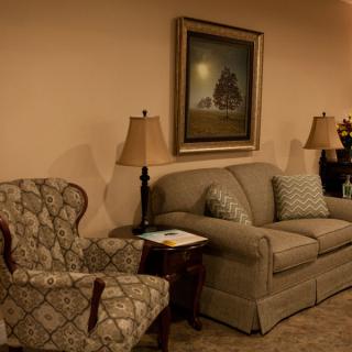 A cozy living room with a sofa, armchair, and decorative lamps.