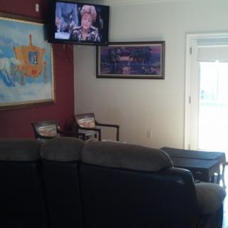 A cozy living room with a couch, artwork on the walls, and a television mounted above.