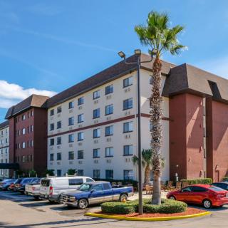 A hotel building with a parking lot and palm trees on a sunny day.