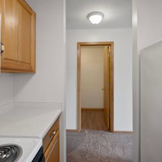 A view of a kitchen area leading to a hallway in an apartment.