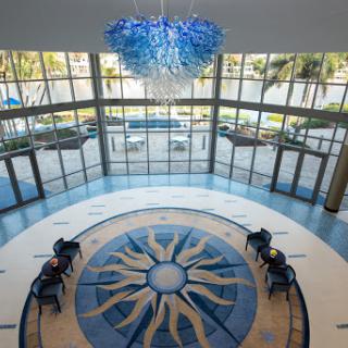 A spacious lobby featuring a unique chandelier and elegant floor design, illuminated by natural light.