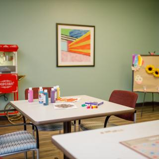 A well-equipped classroom with art supplies on tables and a popcorn machine in the corner.