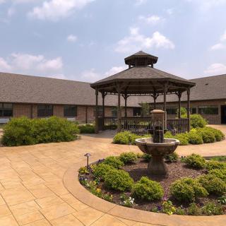 A courtyard featuring a gazebo and fountain surrounded by lush greenery.