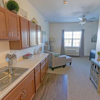 A cozy apartment with an open kitchen and living area featuring wooden cabinets and a large window for natural light.
