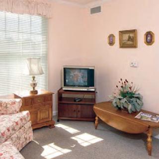 A cozy living room featuring floral-patterned furniture and a vintage television.